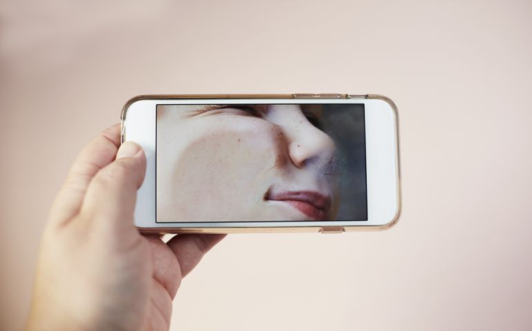 Young boy with his face pressed against digital tablet screen
