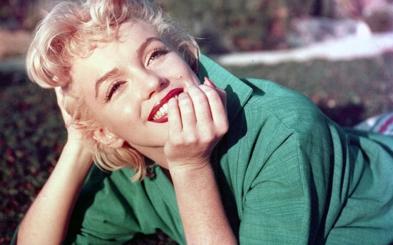 PALM SPRINGS, CA - 1954: Actress Marilyn Monroe poses for a portrait laying on the grass in 1954 in Palm Springs, California.