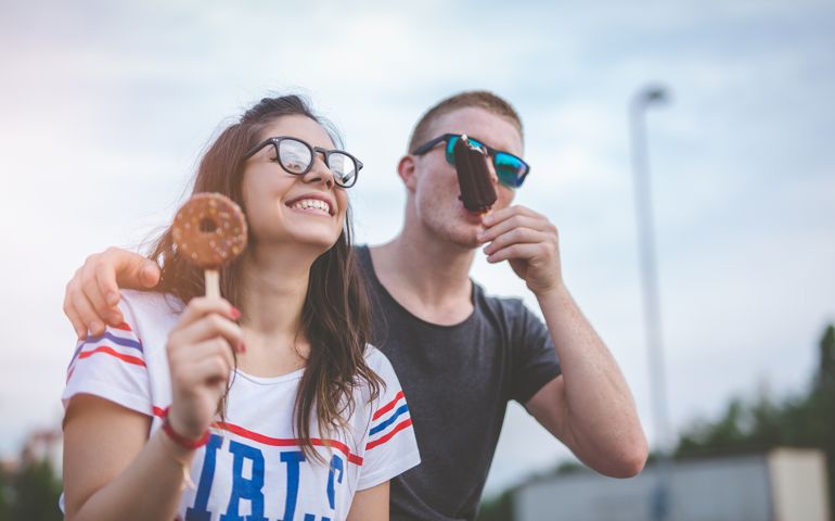 A hugged and smiling couple eating ice cream.T