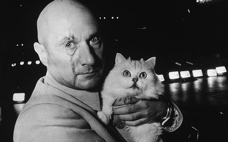 British actor Donald Pleasence (1919 - 1995) in character as Ernst Stavro Blofeld, holding a white cat on the set of the James Bond film 'You Only Live Twice', 24th November 1966.