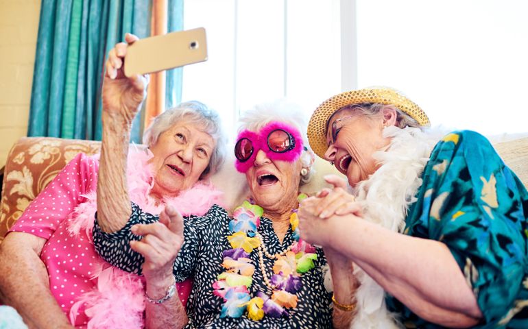 Shot of a group carefree elderly people wearing funky costumes and getting close for a selfie inside of a building