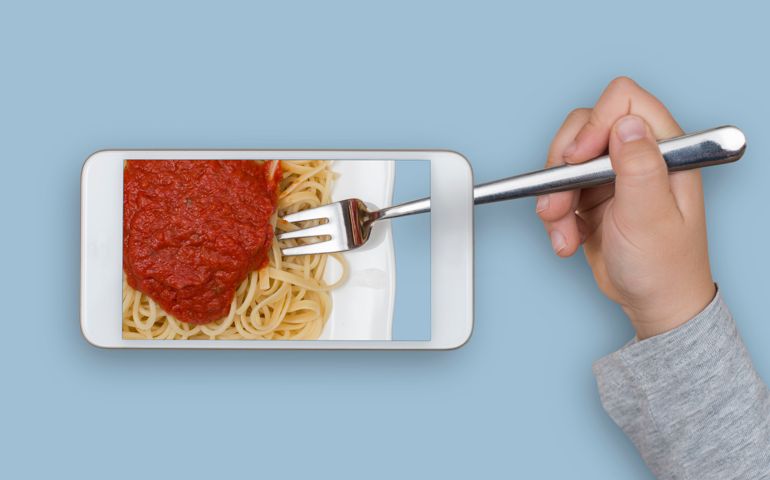 Spaghetti taken through mobile phone screen with fork