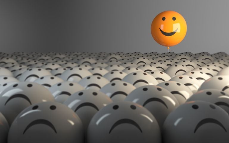 Smiling Sphere Balloon in the middle of grey crowd.
