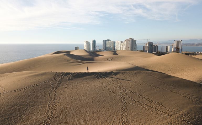 Woman Standing on top of a dune overlooking skyline and sea