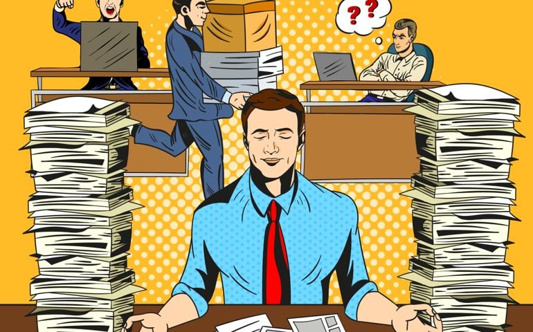 Overworked stressed businessman relaxing practicing yoga in the office, meditating with closed eyes to de-stress flanked by two tall stacks documents