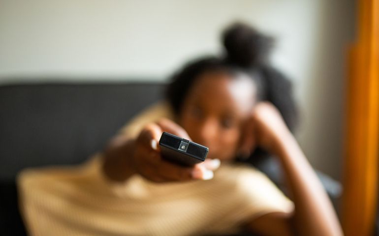Close up portrait african american girl relaxing with tv remote control