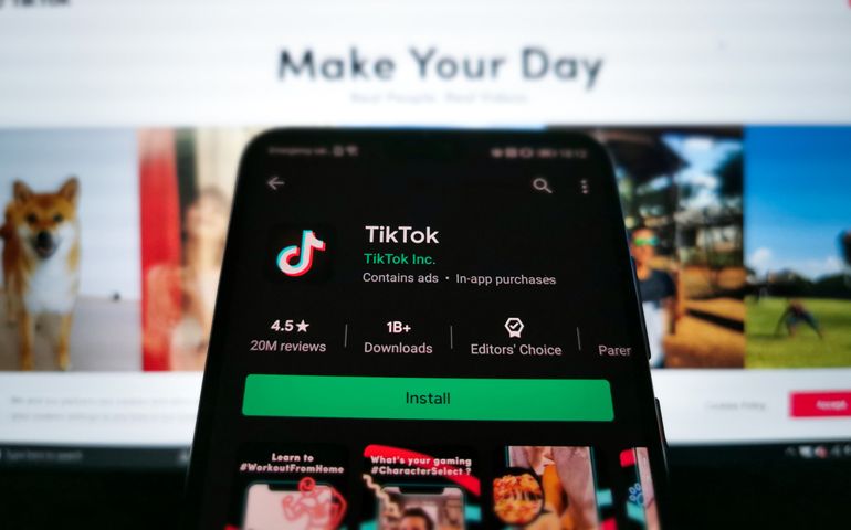 A picture of the TikTok download screen on Google Play Store on an Android phone, with the Tiktok website on the background