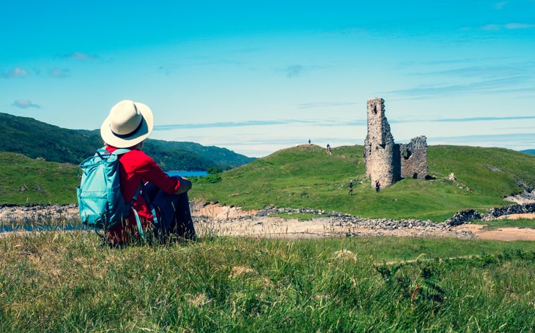 Woman looking at the ruins of Ardvreck Castle just north of the village of Inchnadamph in the Sutherland region of Scotland.