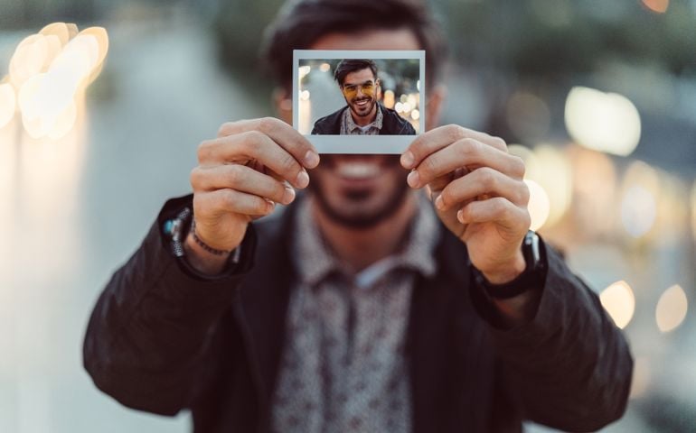 Man showing polaroid portrait to the camera
