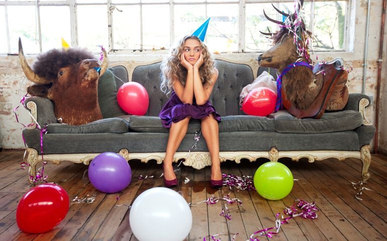 Comic scene of a bored young woman at a party sitting between two "party animals" - a stag and a bull.