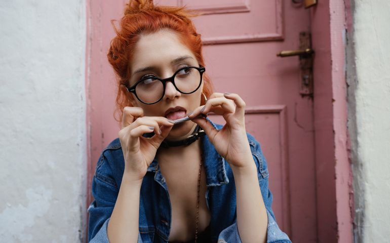 Young woman roll-up cigarette sitting at the entrance of an old house