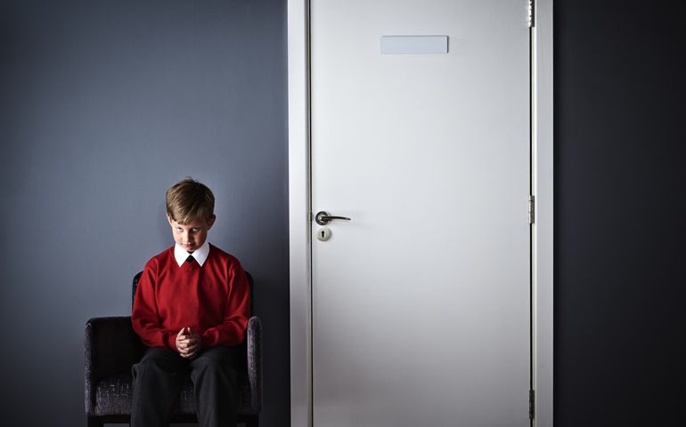 Little boy sitting in front of headmaster office
