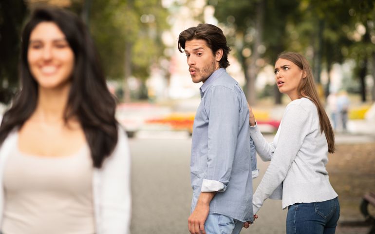 Jealousy. Jealous Girlfriend Calling Boyfriend Distracted By Other Attractive Woman Walking During Date In Park. Selective Focus