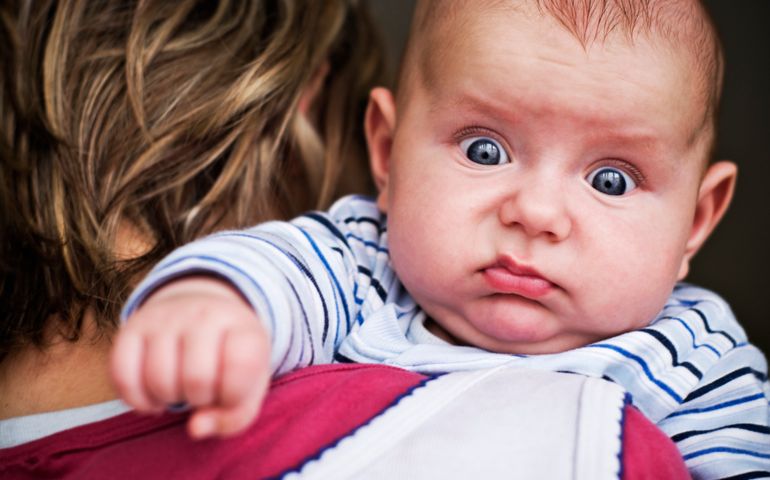Baby boy looking with funny expression.