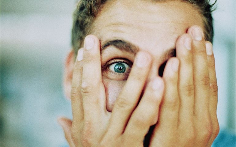 Man peeping through fingers, portrait, close-up