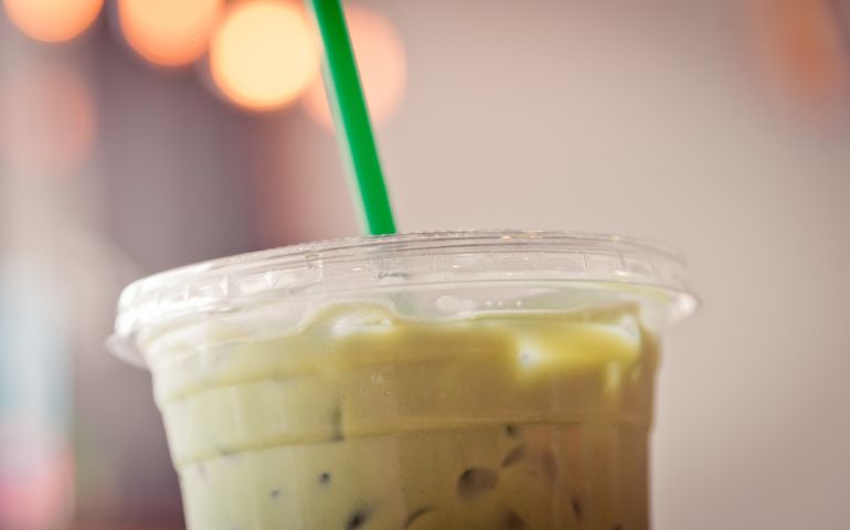 Plastic cup of Iced matcha with green straw in creamy tone