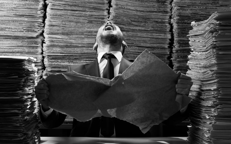 Office worker tearing up papers and screaming out due to red tape