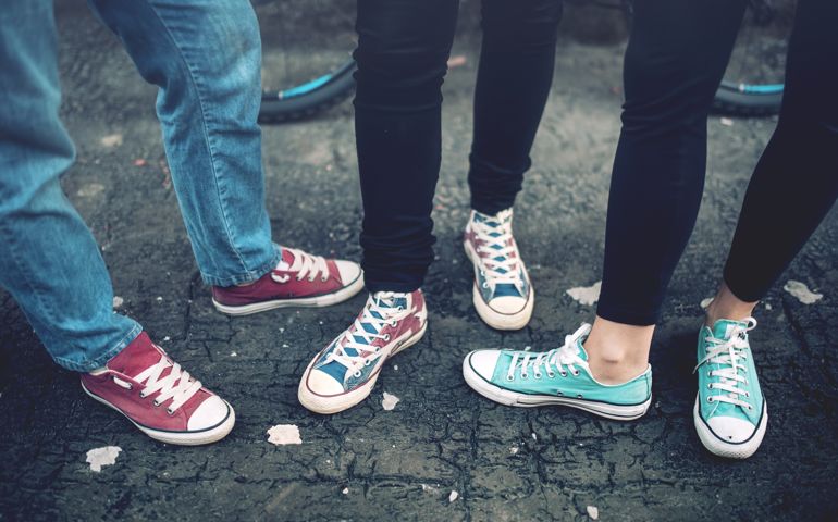 Young rebel teenagers wearing casual sneakers, walking on dirty concrete. Canvas shoes and sneakers on female adults
