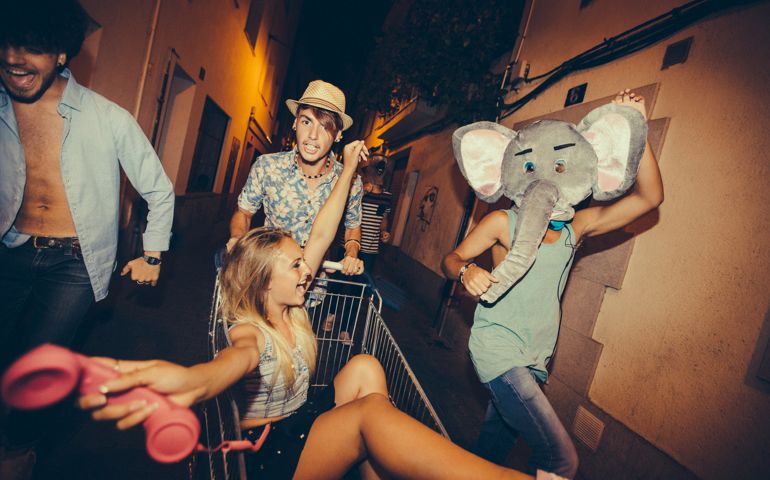 Hipster teenagers partying and being silly with shopping cart in street