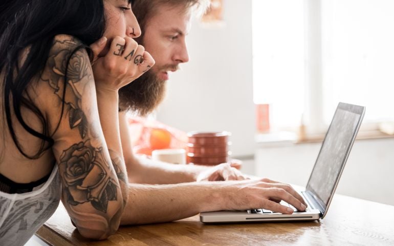 Young couple with Laptop having fun in their kitchen.