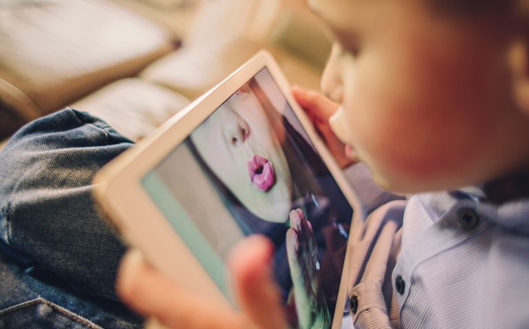 Little boy talking to his working Mother over the internet blowing her a kiss