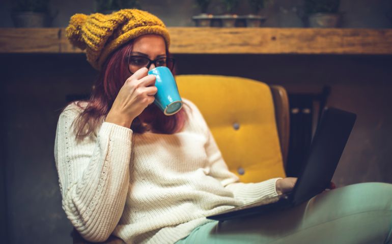 Hipster woman sitting on armchair using a laptop