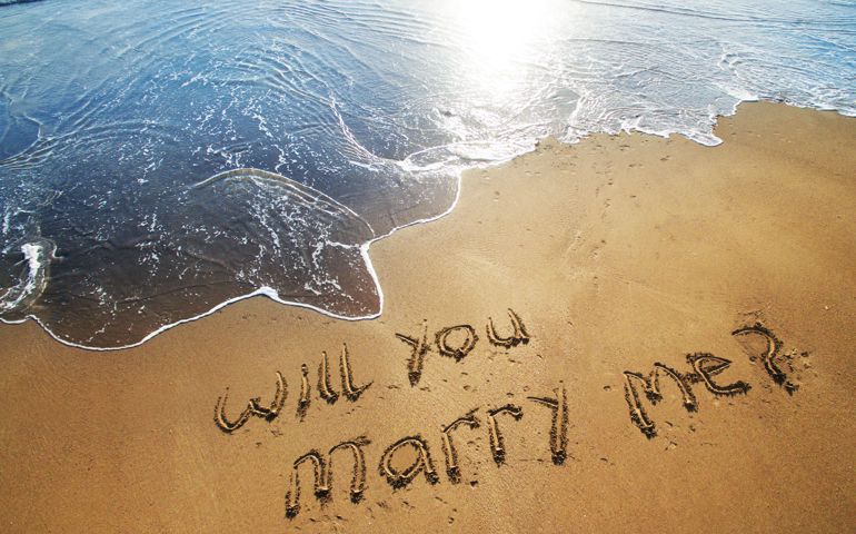 Will you marry me written in sand on beach