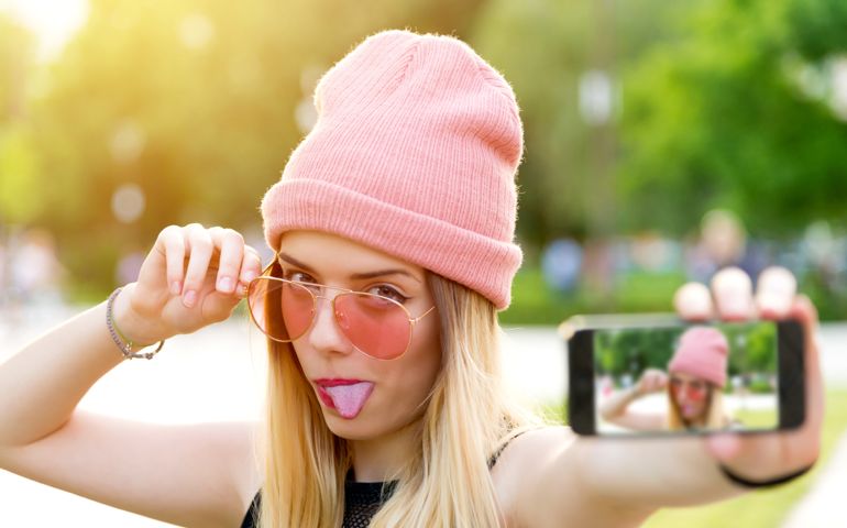 Beautiful woman makes self portrait on smartphone view of screen