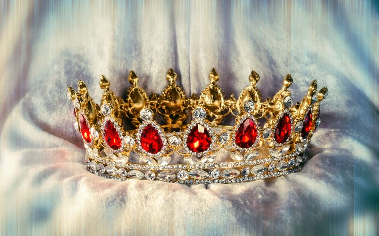 A beautiful crown with red jewels on soft clothes with color effect
