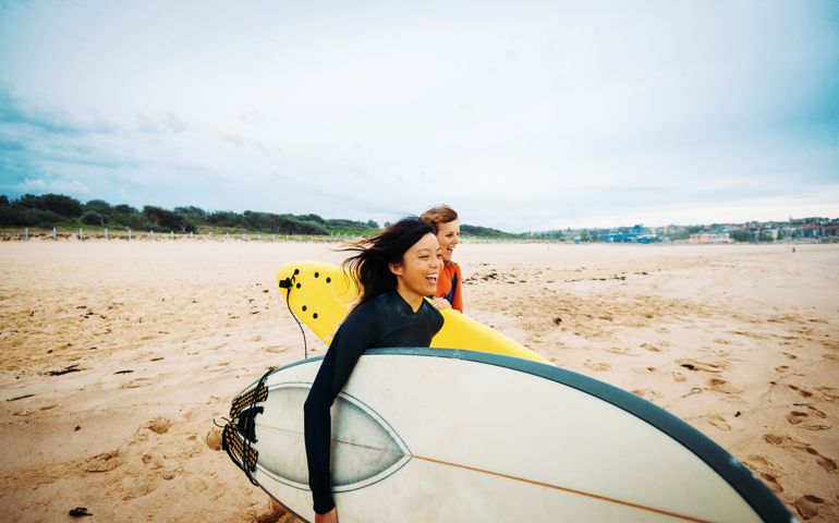 Chinese woman and her Australian friend are going surfing on Sydney beach