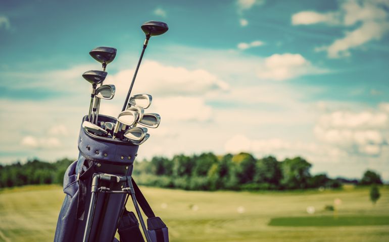 Golf equipment bag standing on a course. Summer sport and activity. Golf clubs close-up.
