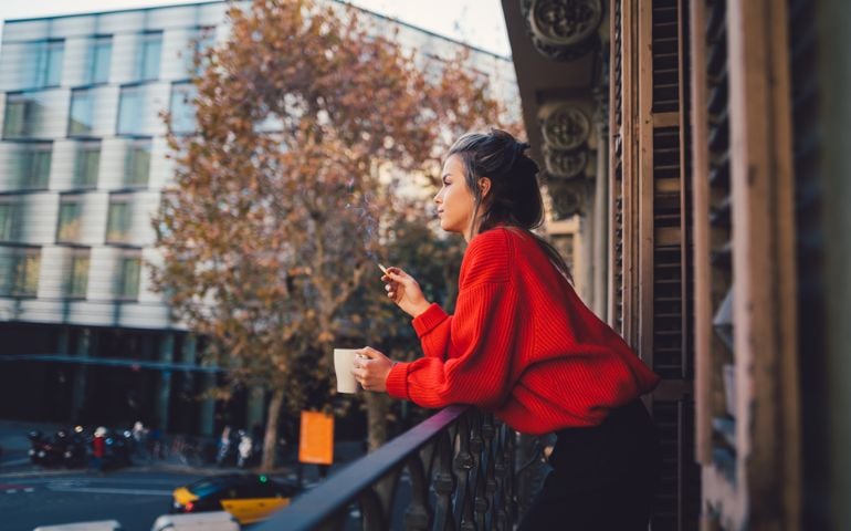 Young woman drinking coffee and smoking at the terrace