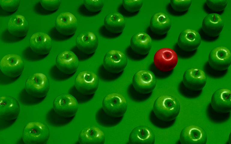 One red apple with many green apples