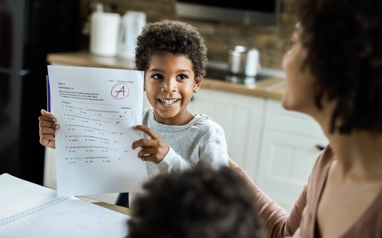 Happy African American boy showing his family a positive results from an exam.