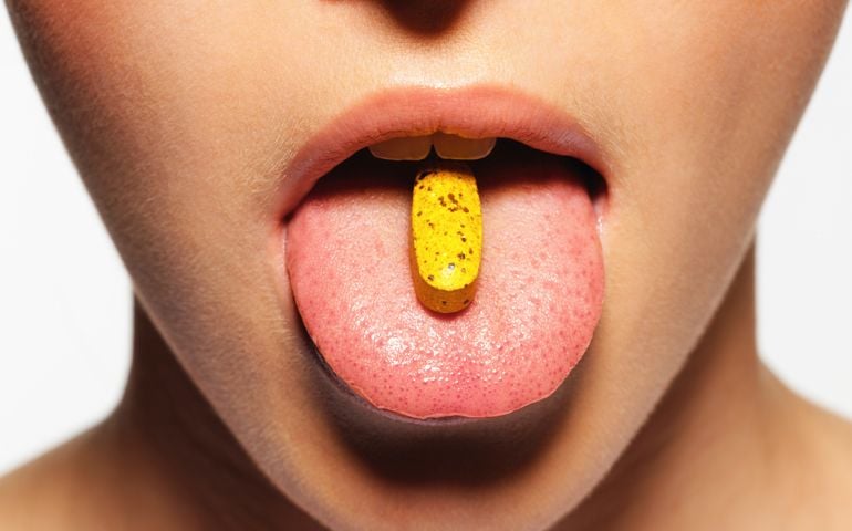 Young woman with pill on tongue, close-up