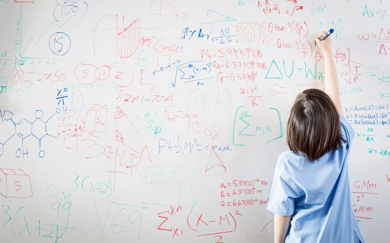schoolgirl in front of white board, writing math