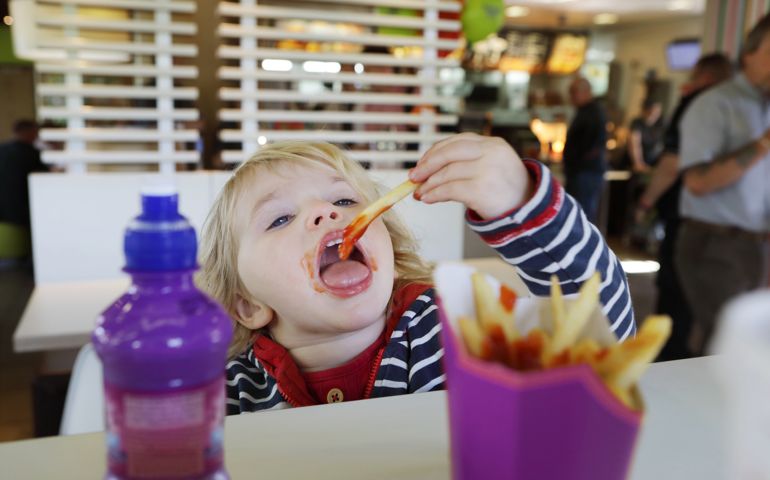 Toddler eating fast food in restaurant