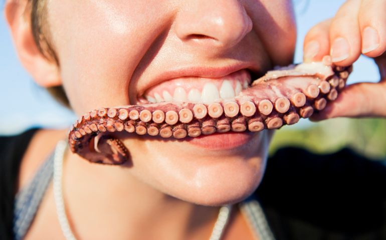 Close-up of young woman biting into octopus tentacle