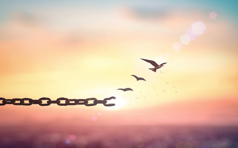 Silhouette of bird flying and broken chains at beautiful mountain and sky autumn sunset background
