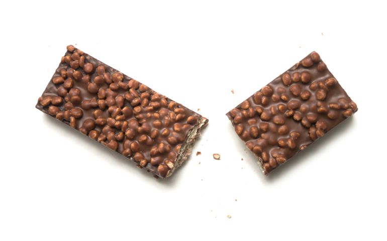 Closeup of broken chocolate bar with puffed rice on white background