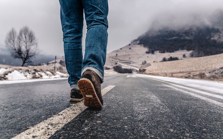 Man walks alone on an empty road in mountains.