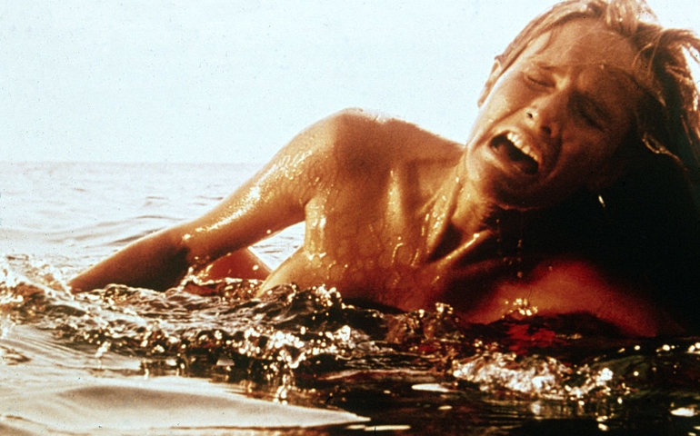 A female swimmer screams as she is attacked by a giant Great White shark (not pictured) in a still from the film 'Jaws,' directed by Steven Spielberg, 1975. (
