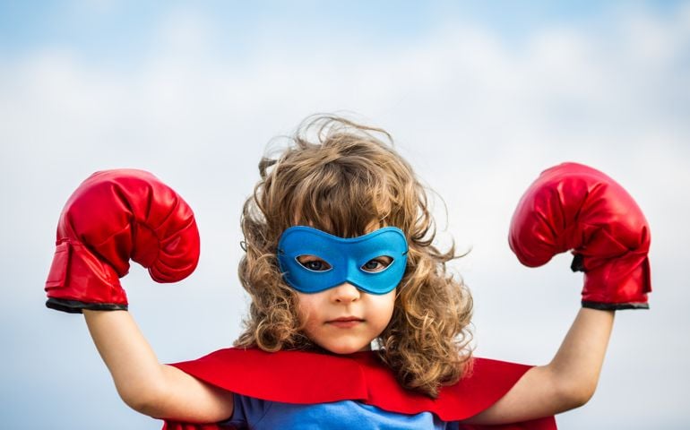 Superhero kid wearing boxing gloves against blue sky background. Girl power and feminism concept