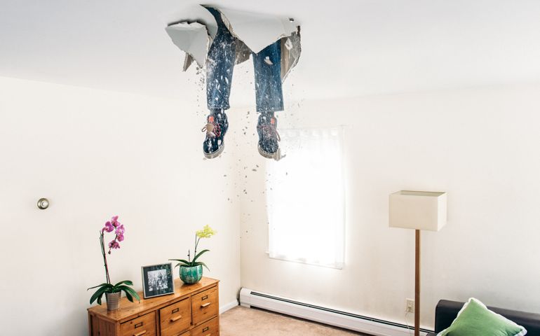 Man breaks ceiling drywall while doing home improvements.