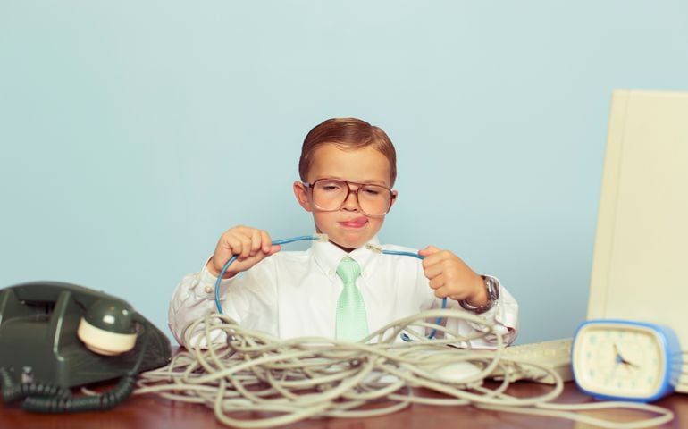 A young IT professional working with a large pile of tangled internet cables on his desk. He is dressed in a white shirt, tie and glasses while trying to reconnect his broken network. Retro styling. This IT technician can solve any network problem.