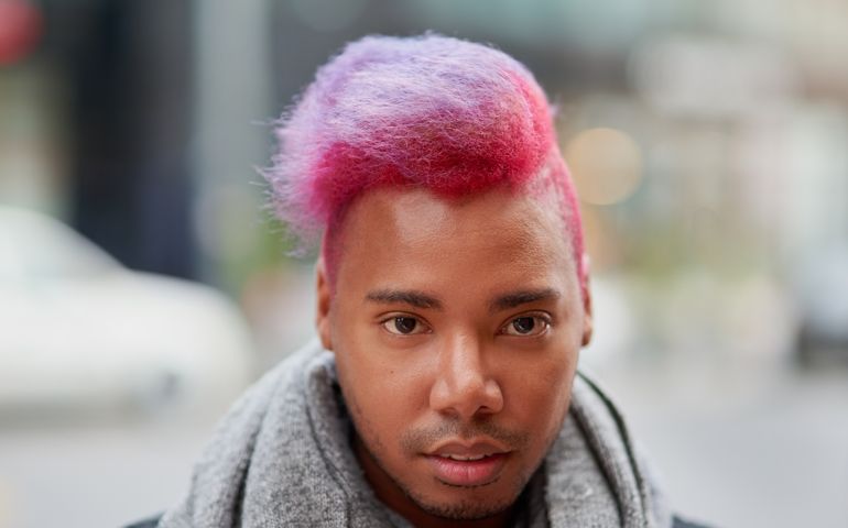 Portrait of a young man with a funky hairstyle posing outdoors