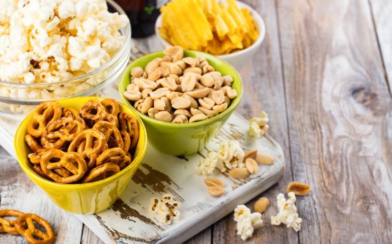 Beer snacks on wooden table - nuts, chips and popcorn in bowls ready for eating. Football fan party. Copy space