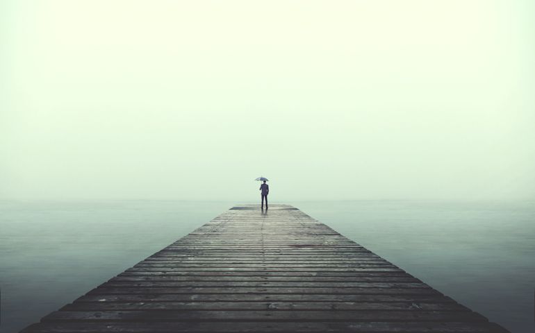 Sad business man with umbrella looking at the horizon