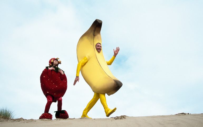 Man dressed as a banana and woman dressed as a strawberry on a beach