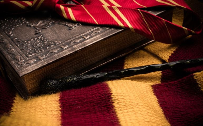 Subjects of the school of magic. Scarf, magic wand, book of spells on grey dark rag background.
